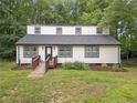 Home featuring a wooden ramp, black framed windows, and fresh landscaping, surrounded by a lush lawn and greenery at 172 White Rose Ln, Temple, GA 30179