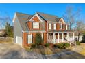 Elegant brick home with a side-entry garage, a covered porch, and mature trees at 4055 Inman Park Ln, Buford, GA 30519