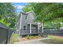 Two-story home featuring gray siding, a welcoming porch, and a fenced yard with lush greenery at 935 Pelham Nw St, Atlanta, GA 30318