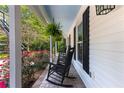 Inviting front porch featuring classic rocking chairs, brick flooring, and vibrant floral accents at 12550 Hutcheson Ferry Rd, Palmetto, GA 30268