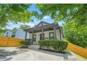 Charming home featuring a covered front porch with a ceiling fan, surrounded by lush greenery and mature trees at 556 Paines Nw Ave, Atlanta, GA 30318