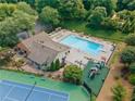 An aerial view of a community pool, tennis court and playground area surrounded by lush greenery at 3436 Laurelwood Ne Ct, Roswell, GA 30075