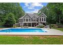 Backyard oasis featuring a sparkling pool, a spacious patio, and a two-story gray house at 9125 Patrick Pl, Winston, GA 30187