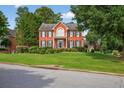 Two-story brick home with manicured lawn, landscaped bushes, trimmed trees, blue shutters and a balcony at 2559 Dunhaven Gln, Snellville, GA 30078
