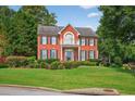 Two-story red brick home featuring a balcony, manicured lawn and bushes, with lush green trees in the background at 2559 Dunhaven Gln, Snellville, GA 30078