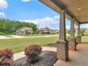 Inviting covered porch with brick-based columns and views of the landscaped front yard and neighboring homes at 149 Elkins Blvd, Locust Grove, GA 30248