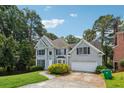 Two-story home with a well-manicured lawn, lush greenery, and attached garage at 4467 Boatmans Cv, Stone Mountain, GA 30083