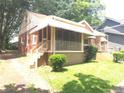 Cozy brick home featuring a covered porch, manicured bushes and mature trees at 1712 Clifton Se Way, Atlanta, GA 30316