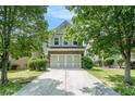 Two-story home with brick and siding, attached garage, driveway, and mature trees in the front yard at 2100 Lily Valley Dr, Lawrenceville, GA 30045