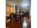 Dining area with wooden floors, a dark wood table with chairs, and a view into the kitchen on a sunny day at 2545 Melville Pl, Powder Springs, GA 30127