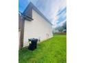 Side yard view with grass and a trash can near the siding of a house on a sunny day at 2545 Melville Pl, Powder Springs, GA 30127