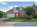 Traditional brick home with dormers above the garage featuring a pristine lawn and lush landscaping at 2000 Stockton Walk Ln, Snellville, GA 30078