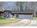 Charming home featuring grey siding, a black roof, a well-manicured lawn, and an attached garage at 8212 Englewood Trl, Riverdale, GA 30274