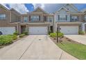 Exterior view of a well-maintained townhome featuring a one-car garage and manicured landscaping at 2638 Village Park Bnd, Duluth, GA 30096
