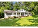 Inviting single-story home featuring a white brick exterior, a cozy front porch, and lush landscaping at 3999 Phils Ct, Tucker, GA 30084