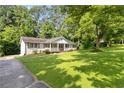 Well-maintained house with a lush front yard and a cozy porch, surrounded by mature trees at 3999 Phils Ct, Tucker, GA 30084