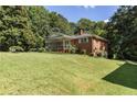 View of a brick home with a lush green lawn and mature trees at 5670 Lanny Dr, Powder Springs, GA 30127