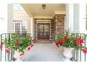 Charming front door entrance featuring brick accents, flanked by beautiful potted plants, and a 'Welcome' doormat at 1432 Arbor Bluff Ct, Lawrenceville, GA 30045