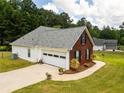 Angle view of a brick house with an attached garage, lush lawn, and mature trees, set back for privacy at 15 Fairwoods Ct, Covington, GA 30016