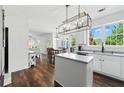Bright kitchen featuring white cabinets, an island, and an adjacent dining area at 312 Laurel Run Cv, Sugar Hill, GA 30518