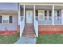 Covered front porch with a brick foundation and white railings leading to the front door at 4185 Duesenberg Dr, Tucker, GA 30084