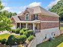 Brick home with a manicured lawn, a side-entry garage, and mature landscaping on a sunny day at 4465 Saint Andrews Crest Dr, Cumming, GA 30040