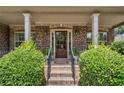 Inviting front porch with brick columns, a glass paneled door, and lush green bushes at 4465 Saint Andrews Crest Dr, Cumming, GA 30040