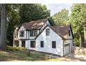 Two-story Tudor style home with white brick and brown trim near a wooded area at 4640 Calleigh Way, Snellville, GA 30039