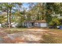 View of house with gray siding, small front porch, attached garage, and yard covered in autumn leaves at 1496 Meadowlark Dr, Decatur, GA 30032