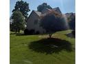 View of the backyard of a two-story home with abundant trees, blue skies and a large lawn at 2580 Three Wood Dr, Villa Rica, GA 30180