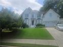 Charming home with a manicured front lawn, two-car garage, and a welcoming entryway under a cloudy sky at 9035 Sandorn Dr, Roswell, GA 30075