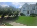 Lush front yard with a beautiful lawn leading up to an elegant home, framed by mature trees and landscaping at 9035 Sandorn Dr, Roswell, GA 30075