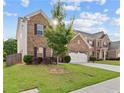 Inviting two-story home with a lush green lawn and a tree providing shade in the front yard at 1742 Weatherbrook Cir, Lawrenceville, GA 30043