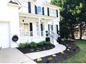 Up close view of a white house with landscaped flower beds and black mulch, complemented by a winding walkway at 6265 Lake Windsor Pkwy, Buford, GA 30518