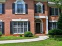 Close-up of a brick home featuring an arched doorway, manicured bushes, and black shutters at 4221 Bretdale Nw Run, Kennesaw, GA 30152