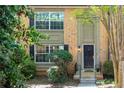 Charming brick townhome showcasing a black front door, complemented by neatly trimmed bushes and lush greenery at 6980 Roswell Rd # N5, Atlanta, GA 30328