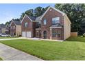 Two-story brick home featuring a well-manicured lawn, two-car garage and view of neighboring houses at 802 Cormac Dr, Riverdale, GA 30296