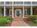 Inviting entryway boasting a classic brick facade, arched doorway, and manicured shrubbery at 8935 Muirfield Ct, Duluth, GA 30097