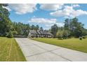 Well-maintained home features a sprawling lawn, a long concrete driveway, and mature trees at 1369 Sierra Ridge Pl, Loganville, GA 30052
