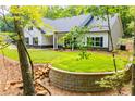Charming one-story home surrounded by lush greenery and manicured lawn with a stone retaining wall at 5525 Belle Meade Dr, Villa Rica, GA 30180
