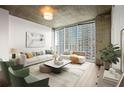 Living room with modern furniture, large windows, and concrete ceilings at 855 Peachtree Ne St # 2205, Atlanta, GA 30308