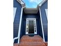 Close-up of a classic black front door with sidelights, complemented by brick steps and blue siding at 3337 Camens Way, Buford, GA 30519