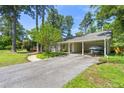 View of driveway leading to a covered carport with a boat, framed by mature trees and landscaping at 1444 Arden Sw Dr, Marietta, GA 30008