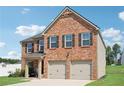 View of the brick exterior elevation of the home with attached two-car garage at 1363 Midnight Ride Ct, Hampton, GA 30228