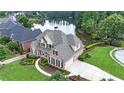 Beautiful home with mature landscaping, a circular driveway, and a serene lake view at 1375 Highland Lake Dr, Lawrenceville, GA 30045