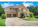 Beautiful brick home featuring an attached two-car garage, lush landscaping and a curved driveway at 4715 Mcintosh Drive Dr, Cumming, GA 30040