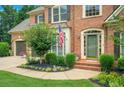Inviting front entrance of brick home, featuring a two-car garage, landscaped garden, and green front door at 4715 Mcintosh Drive Dr, Cumming, GA 30040