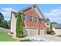 Side view of a brick home with three car garage, well maintained lawn, and manicured greenery at 5689 Woodland Greens Rd, Douglasville, GA 30135