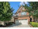Beautiful brick home exterior showcasing a two-car garage and mature trees at 49 Braemore Mill Dr, Lawrenceville, GA 30044
