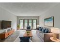 Bright living room featuring a comfortable gray sofa, a modern TV, and glass doors to a balcony at 3650 Ashford Dunwoody Rd, Ne, #923, Atlanta, GA 30319